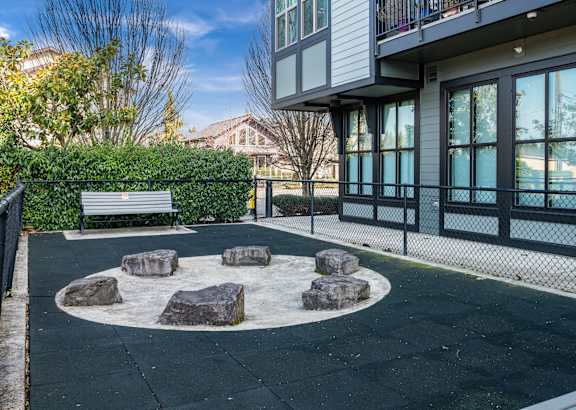 a park with a bench and rocks in front of a building