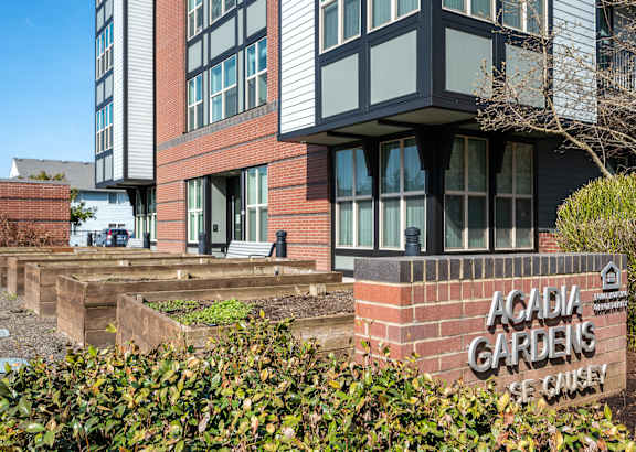 a picture of the front of a building with a sign that reads acadia gardens