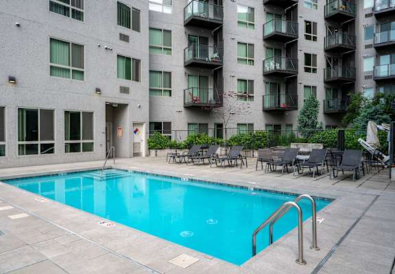 A small pool in a courtyard surrounded by chairs and buildings.