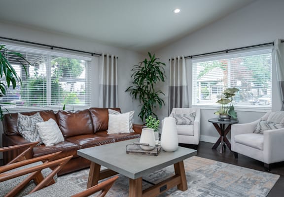 A living room with a brown leather couch, a white armchair, and a wooden coffee table.