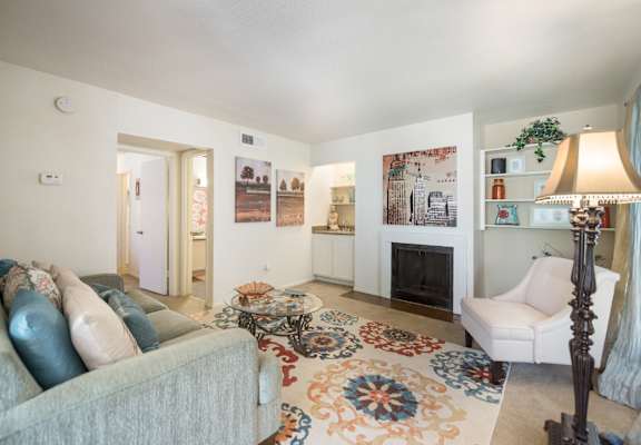 A living room with a grey couch and a rug with a flower design.