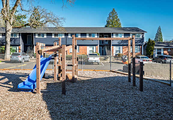 A playground with a blue slide and a wooden structure.