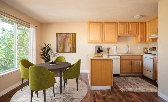 A kitchen with a table and chairs in the foreground and a painting on the wall.