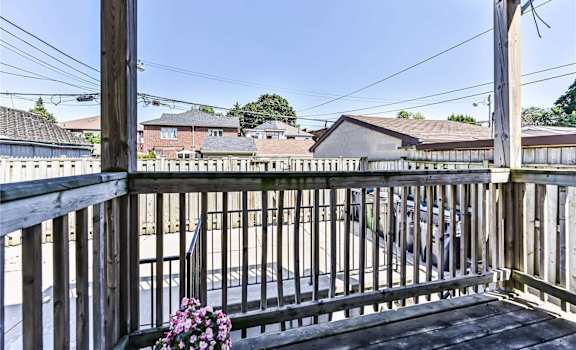 A wooden deck with a metal railing and a potted plant on it.
