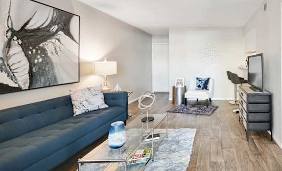a living room with a blue couch and a glass coffee table