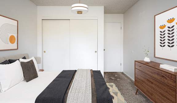 A room with a white couch, a black and grey rug, and a painting on the wall.