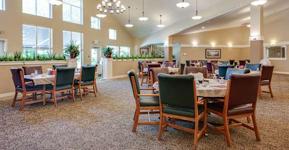 A large room with tables and chairs is well lit with natural light.