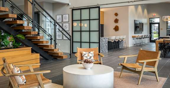a living room with chairs and a table and a staircase