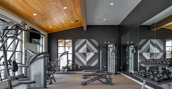 a fitness room with weights and cardio equipment and a wall of windows
