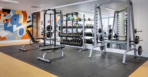 A gym with a variety of equipment including weights and weight machines.