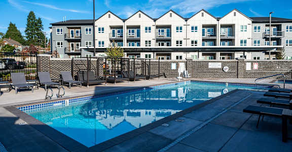 a swimming pool with an apartment building in the background