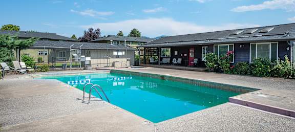 A swimming pool in front of a building with a sunny sky.