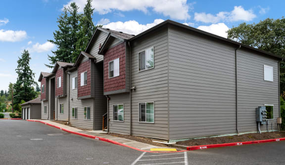 a row of condominiums with gray siding and red trim