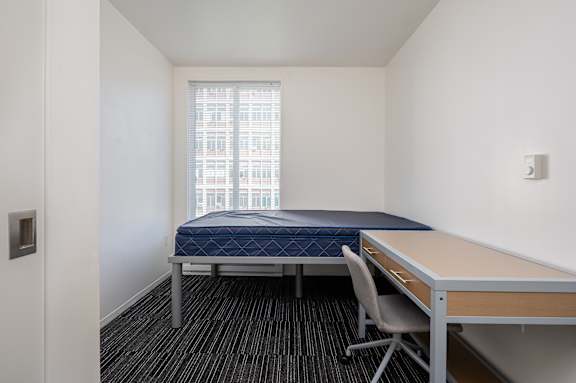 A bedroom with a bed, desk, and chair.