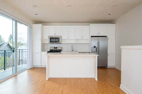 A kitchen with white cabinets and a wooden floor.