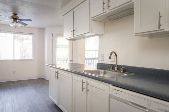 an empty kitchen with white cabinets and a sink