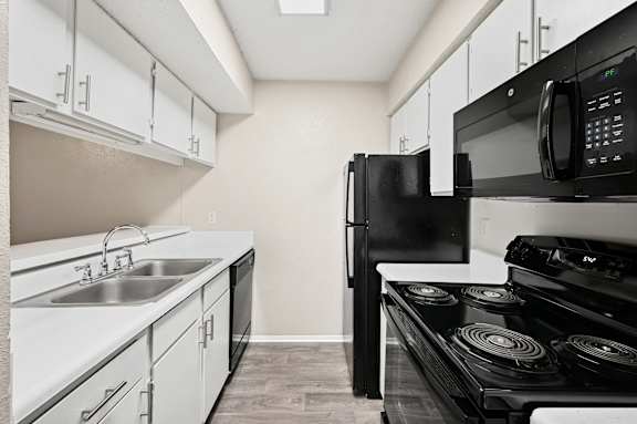 A black microwave is on top of a black stove.