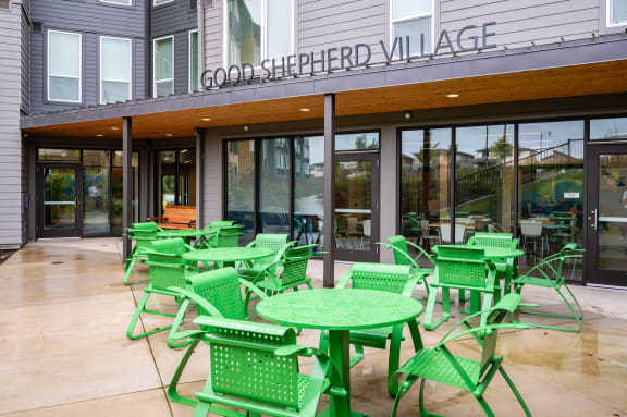 a patio with green chairs and tables outside of a restaurant