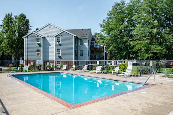 A swimming pool in front of a grey apartment building.