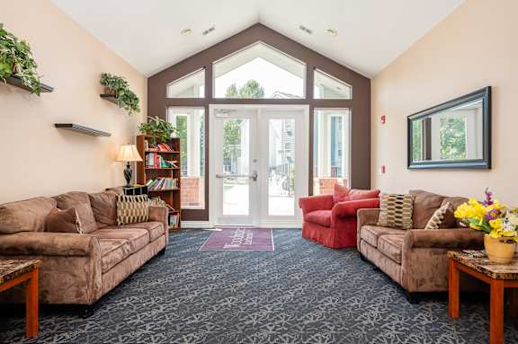 A living room with a couch, chair, and a potted plant.