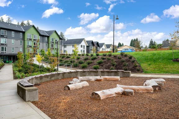 a playground with logs and houses in the background
