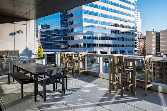A patio with a table and chairs overlooks a large building.