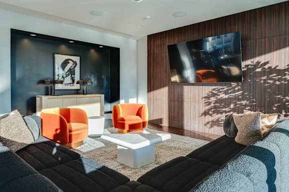 A modern living room with a black and orange color scheme.