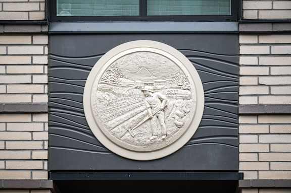 A circular stone plaque with a relief of a man and a woman is mounted on a wall.