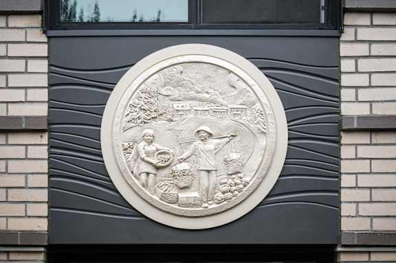 A circular relief sculpture on a building's facade depicting a scene with multiple figures.