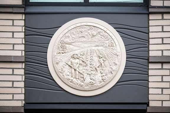 A circular stone plaque with a coat of arms is mounted on a dark wall.