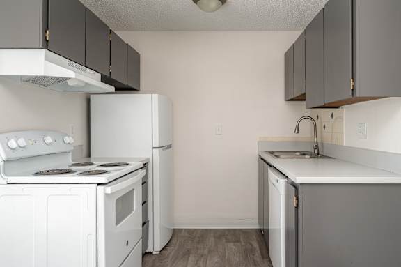 A kitchen with white appliances and grey cabinets.