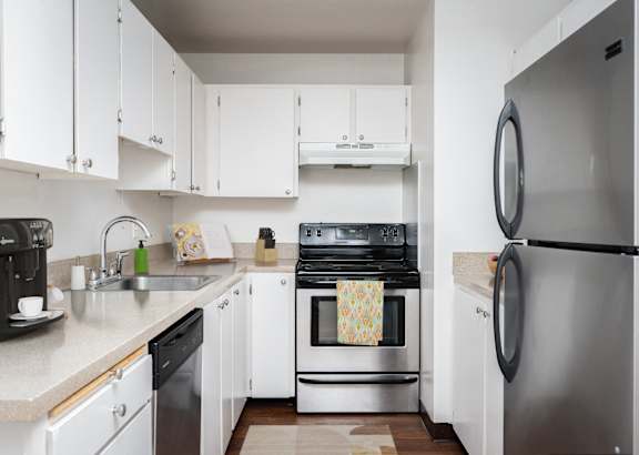 A kitchen with white cabinets and a stainless steel refrigerator.