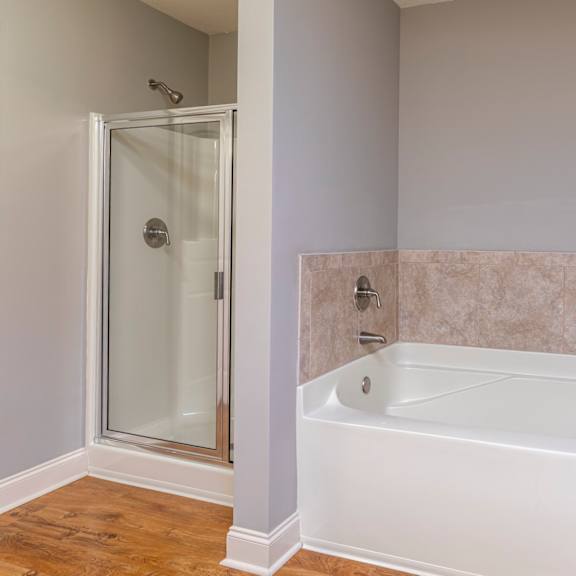 A white bathtub with a glass shower door in a bathroom.
