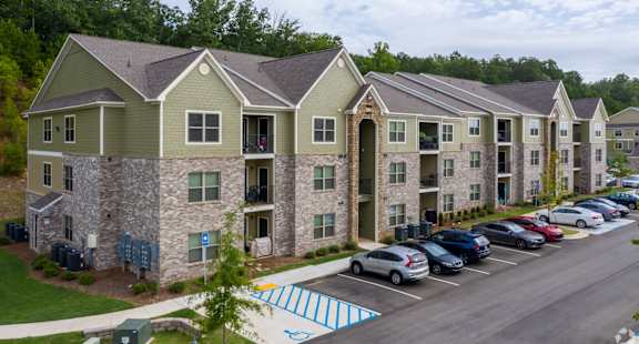 Apartment complex with a parking lot in front.