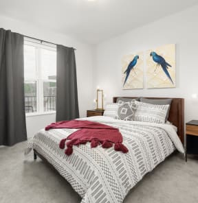 a bedroom with a bed with white bedding and a painting of two blue birds on the