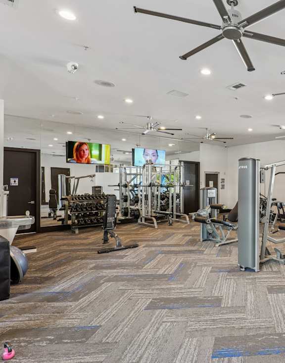A gym with a variety of equipment including treadmills, weights, and exercise machines.