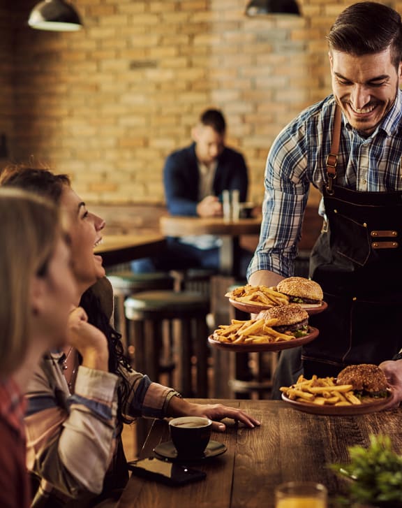a waiter serves burgers to a group of people in a restaurant