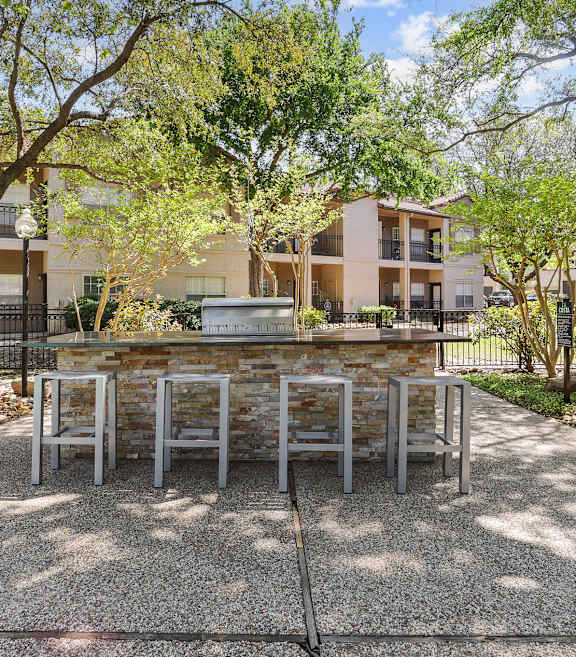 a patio with a table and chairs and trees in the background
