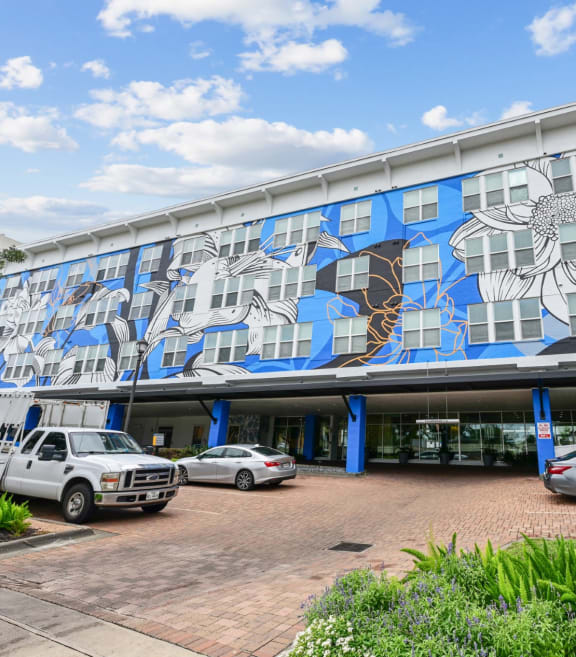 Building exterior with a large floral mural at The Grand at Upper Kirby apartments in Houston, TX