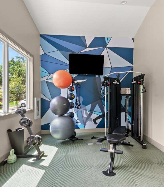 Retreat at Indian Lake Apartments in Hendersonville, TN.. Fitness Center with cardio machines and a large window showing a view of the swimming pool.