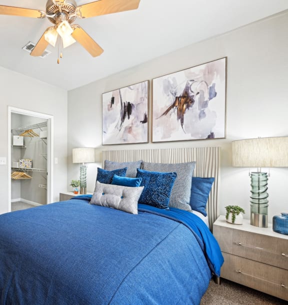 Comfortable bedroom with blue bedding and artistic wall decor at The Grand at Upper Kirby apartments in Houston, TX
