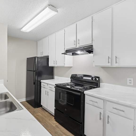 A kitchen with black appliances and white cabinets.