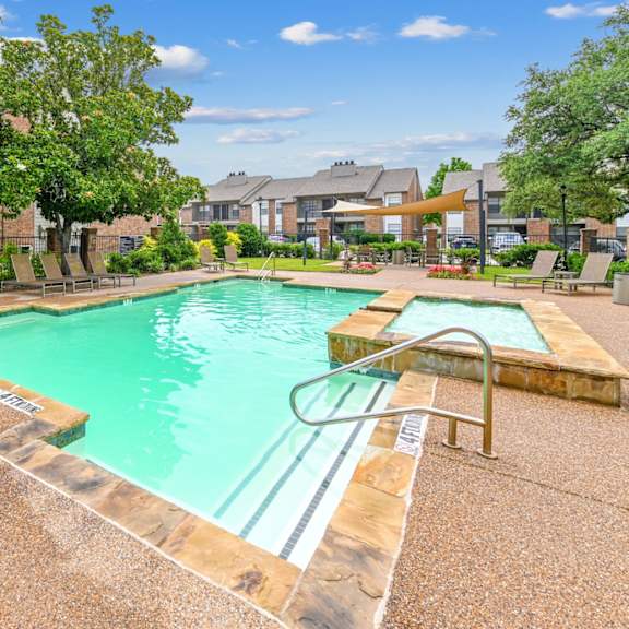 A pool surrounded by a concrete patio and a grassy area.