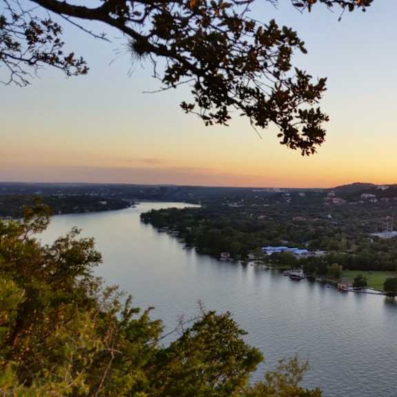 A beautiful sunset view of a lake with a cityscape in the background.
