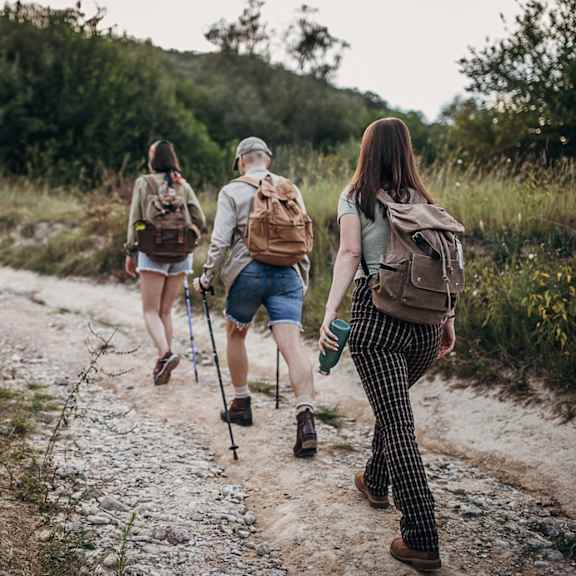Three people are hiking on a gravel path.