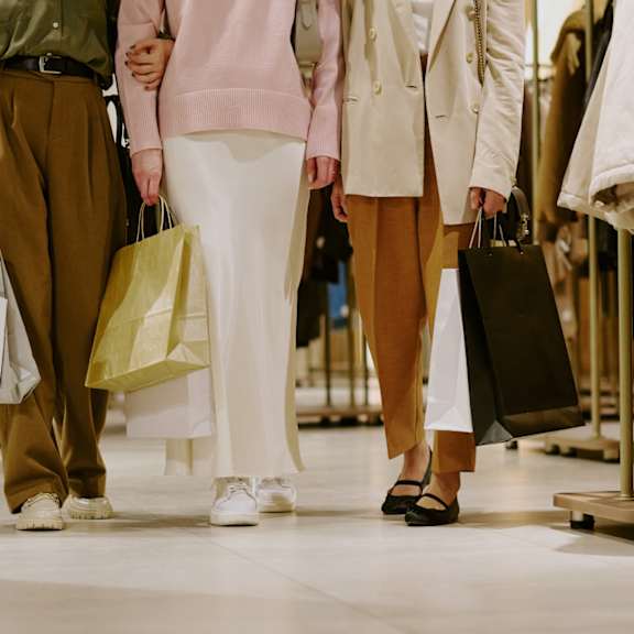 Three people walking in a mall carrying shopping bags.