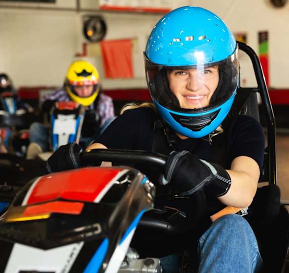 A person in a blue helmet is driving a go-kart in a race track.