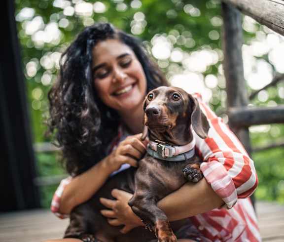 A woman holding a dachshund in her arms.