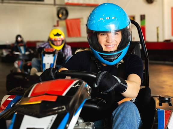 A person in a blue helmet is driving a go-kart in a race track.