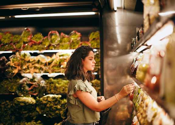 A woman is shopping for produce in a grocery store.